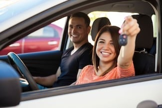 image of a man and a woman in a car with the woman holding up a key